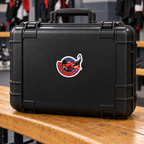 Hockey Joe logo sticker on a black hard equipment case in a hockey locker room — lifestyle mockup.