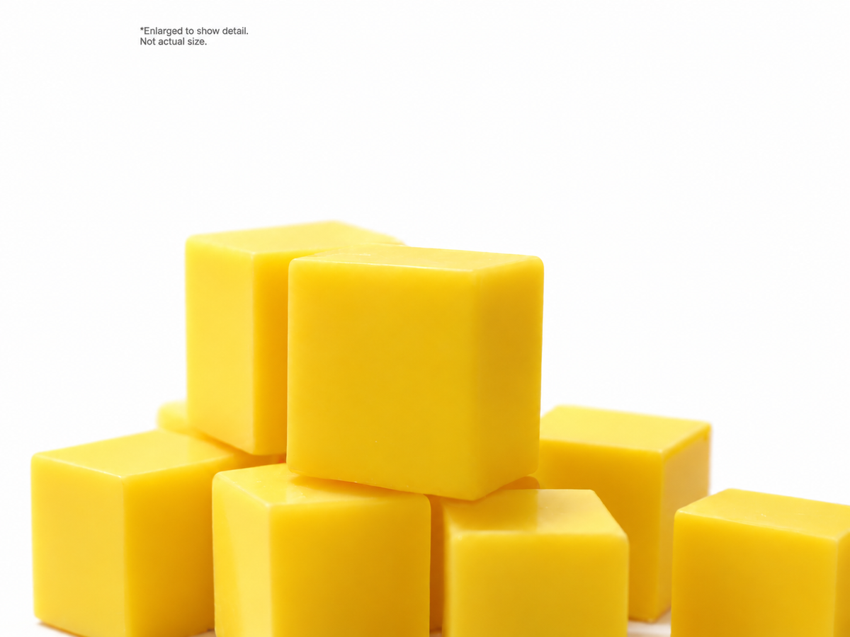 Yellow hockey wax pieces on a white background. Enlarged to show detail, not actual size.